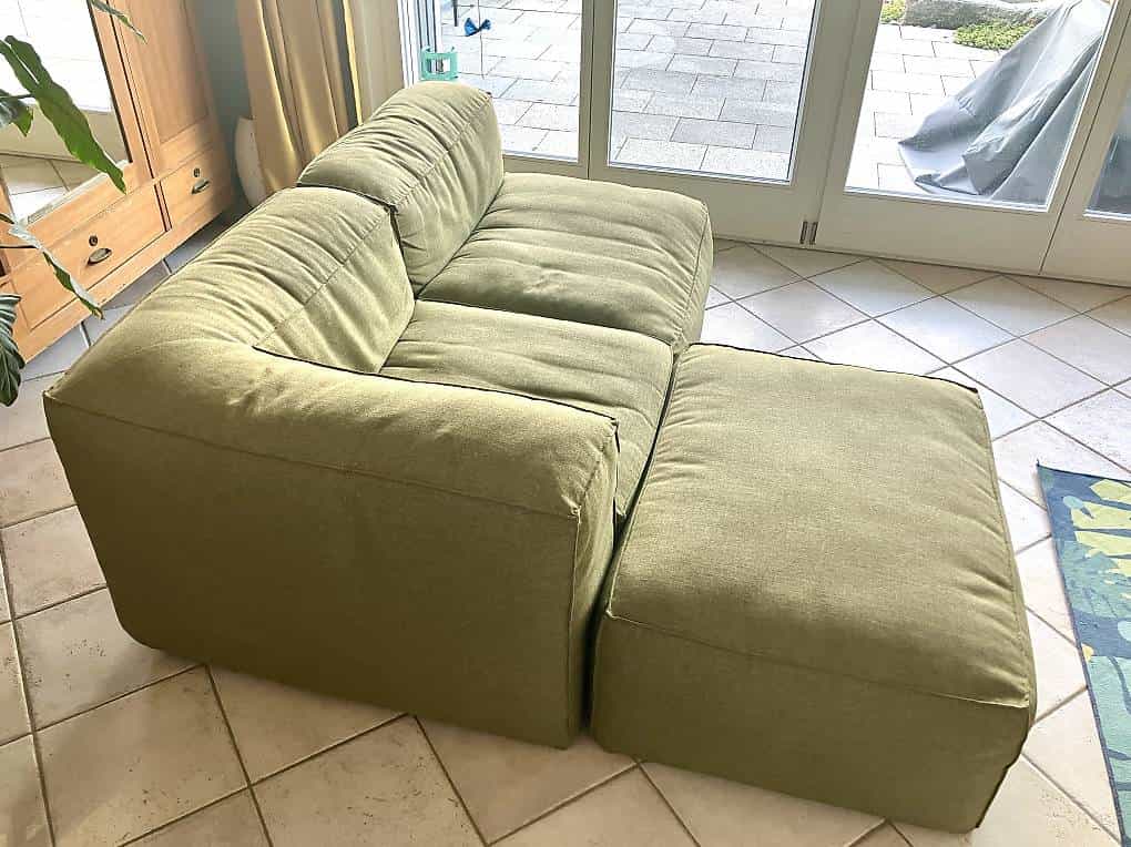 Grünes Stoffsofa mit separatem Beinteil