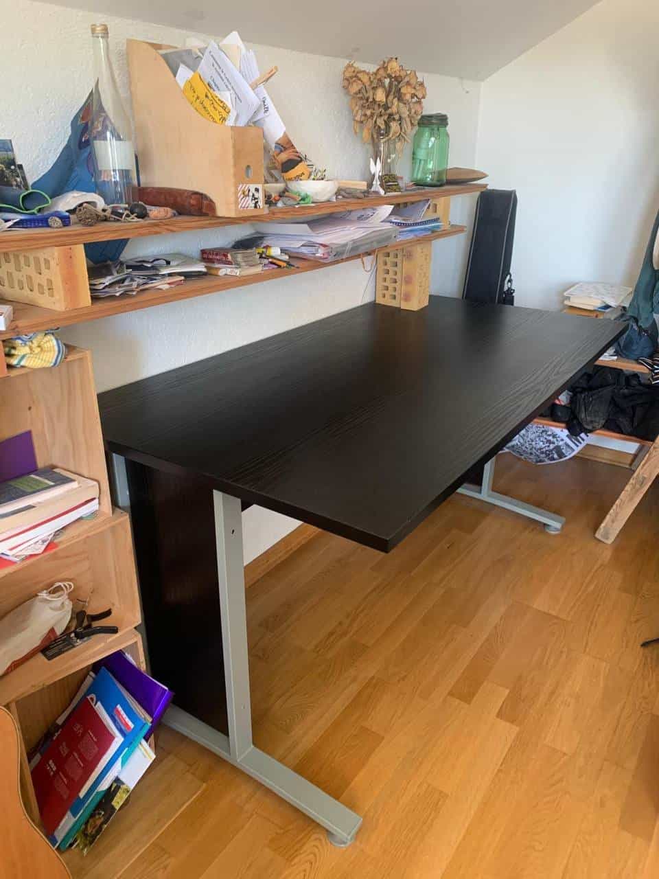 Bureau plateau noir, lit gris capitonné et meubles divers
